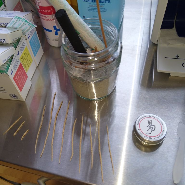 Dosen und Moxastäbchen auf einem Metalltisch.